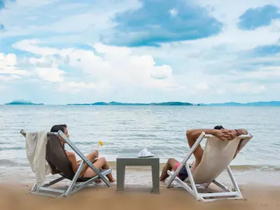 two people sitting in lawn chairs on the beach at Naam Sawan in Ban Pa Khlok