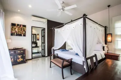 a bedroom with a canopy bed and a chair at VILLA BUTON Private Pool Nai Harn beach in Nai Harn Beach