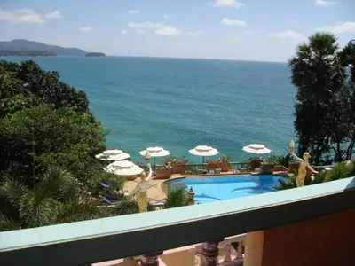 a view of a swimming pool with umbrellas and the ocean at Baan Karon Hill Phuket Resort in Karon Beach