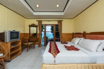 a bedroom with a large bed and a television at Baan Karon Hill Phuket Resort in Karon Beach