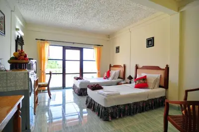 a room with two beds and a kitchen with a window at Baan Karon Hill Phuket Resort in Karon Beach
