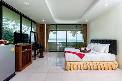 a bedroom with a large bed and a flat screen tv at Baan Karon Hill Phuket Resort in Karon Beach