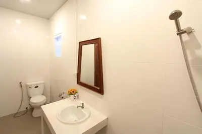 a white bathroom with a sink and a mirror at Choophorn House in Kata Beach