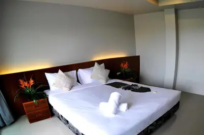 a bedroom with a large white bed with two towels at Choophorn House in Kata Beach