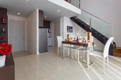 a kitchen and dining room with a table and a staircase at The Aristo by Holy Cow, 2-BR loft, 90 m2, pool view in Surin Beach