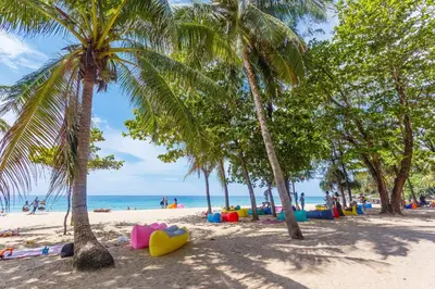 a beach with palm trees and people on the beach at The Aristo by Holy Cow, 2-BR loft, 90 m2, pool view in Surin Beach