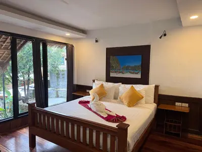 a bedroom with a bed with white sheets and yellow pillows at Chunut House Resort in Phi Phi Don