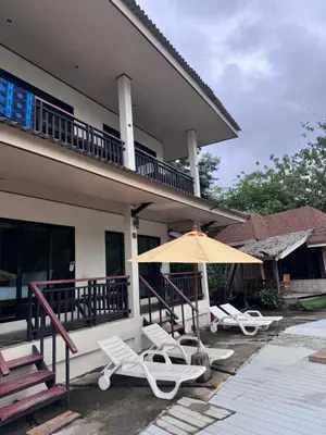 an umbrella and lounge chairs in front of a house at Chunut House Resort in Phi Phi Don