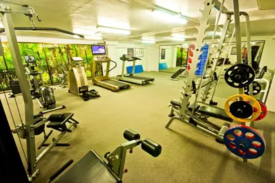 a gym with several treadmills and machines in it at Phuket Orchid Resort and Spa in Karon Beach
