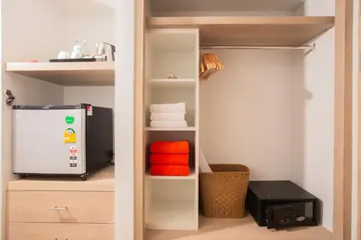 a closet with a refrigerator and some towels at Phuket Orchid Resort and Spa in Karon Beach
