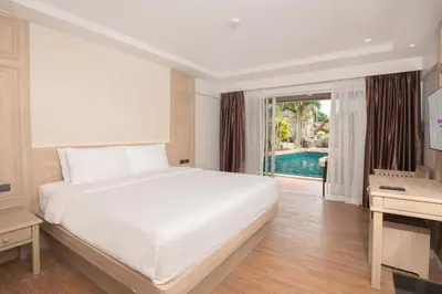 a bedroom with a large white bed and a pool at Phuket Orchid Resort and Spa in Karon Beach