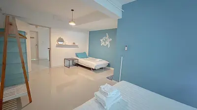 a bedroom with two beds and a table in it at Turtle Rooms in Bang Tao Beach
