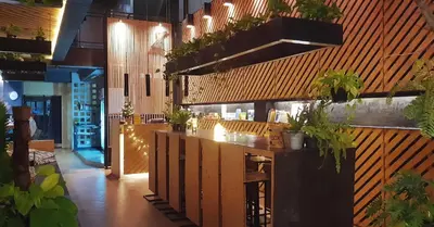 a restaurant with a bar with plants on the wall at Hugger Hostel in Phuket Town