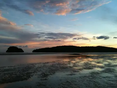 a sunset on a beach with the reflection in the water at The Emerald Krabi Beach Resort in Klong Muang Beach