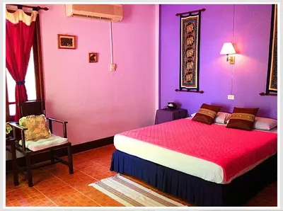 a bedroom with purple walls and a bed and a chair at The Emerald Krabi Beach Resort in Klong Muang Beach
