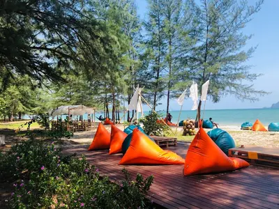 a group of orange pillows on a wooden table at the beach at The Emerald Krabi Beach Resort in Klong Muang Beach
