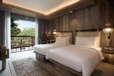two beds in a bedroom with a balcony at Dinso Resort & Villas Phuket, Vignette Collection by IHG in Patong Beach