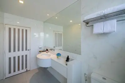 a white bathroom with a sink and a mirror at NH Boat Lagoon Phuket Resort in Phuket Town