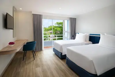 a hotel room with two beds and a desk and a window at NH Boat Lagoon Phuket Resort in Phuket Town