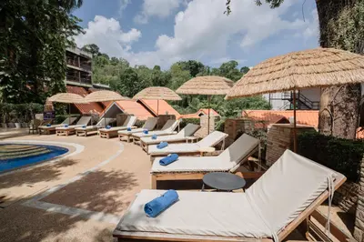 a row of lounge chairs and umbrellas next to a pool at Club Bamboo Boutique Patong Beach Resort in Patong Beach