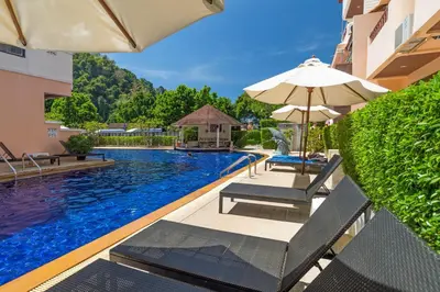 a swimming pool with two chairs and an umbrella at Srisuksant Resort in Ao Nang Beach