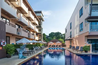 a hotel pool with chairs and umbrellas in a courtyard at Srisuksant Resort in Ao Nang Beach