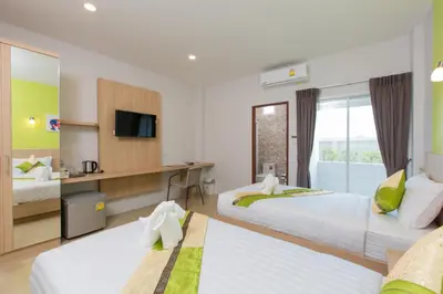 a hotel room with two beds and a television at Phant at Thalang Service Apartment in Thalang