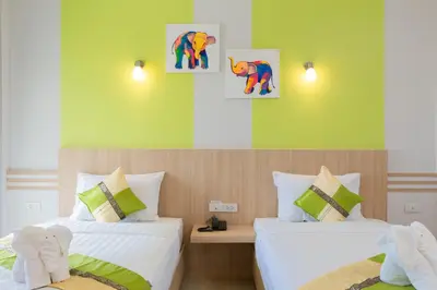 two beds in a room with green and yellow walls at Phant at Thalang Service Apartment in Thalang