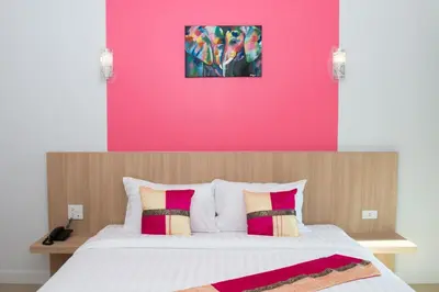 a bedroom with a large bed with a pink wall at Phant at Thalang Service Apartment in Thalang