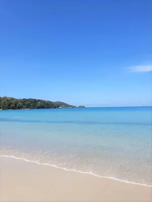 a beach with the ocean and trees in the background at Burasari Phuket Resort & Spa in Patong Beach