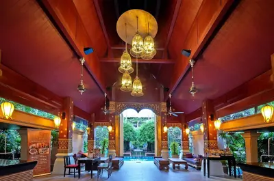 a lobby with tables and chairs and a large window at Burasari Phuket Resort & Spa in Patong Beach