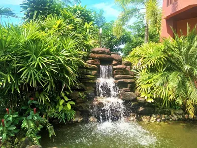 a waterfall in the middle of a pond in a garden at Andamanee Boutique Resort Aonang Krabi - Free Beach Shuttle in Ao Nang Beach