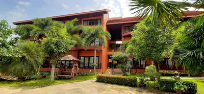 an orange building with trees in front of it at Andamanee Boutique Resort Aonang Krabi - Free Beach Shuttle in Ao Nang Beach