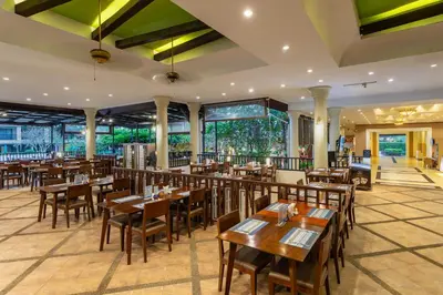a restaurant with wooden tables and chairs and windows at Deevana Patong Resort & Spa in Patong Beach