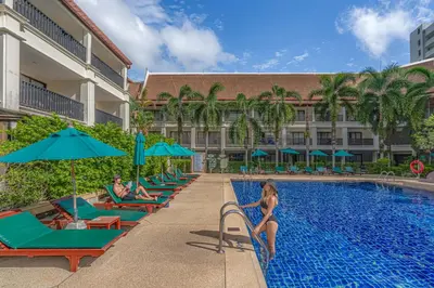 a pool at a hotel with people sitting on lounge chairs at Deevana Patong Resort & Spa in Patong Beach