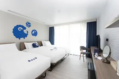 a hotel room with two beds and a blue sign on the wall at Kokotel Krabi Oasis in Ao Nang Beach