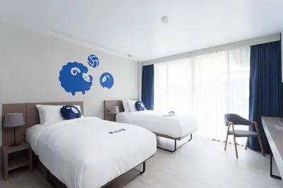 a bedroom with two beds and a blue sign on the wall at Kokotel Krabi Oasis in Ao Nang Beach