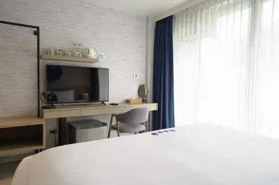 a bedroom with a bed and a desk with a television at Kokotel Krabi Oasis in Ao Nang Beach