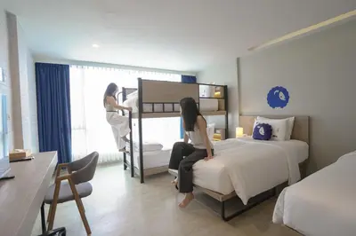 a woman sitting on a bed in a hotel room at Kokotel Krabi Oasis in Ao Nang Beach