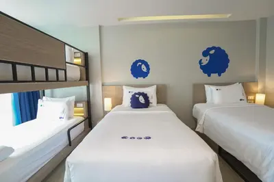 two beds in a room with blue signs on the wall at Kokotel Krabi Oasis in Ao Nang Beach