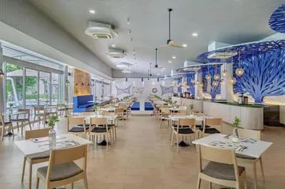 a restaurant with white tables and chairs and blue walls at DoubleTree by Hilton Phuket Banthai Resort in Patong Beach