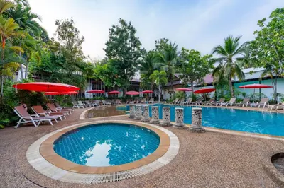 a pool at a resort with chairs and umbrellas at Ao Nang Timber House in Ao Nang Beach