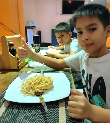 two young boys sitting at a table with a plate of spaghetti at Hotel Sole in Patong Beach