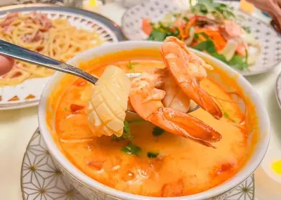 a bowl of soup with shrimp on a spoon at Phuket Signature Glamping in Rawai Beach
