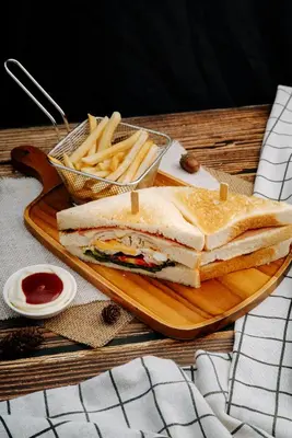 a sandwich and french fries on a wooden cutting board at Blue Tara Hotel Krabi Ao Nang in Ao Nang Beach