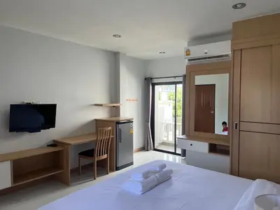 a bedroom with a bed and a desk and a television at J2 Airport Mansion in Nai Yang Beach