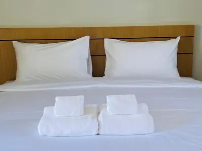 a white bed with two towels sitting on it at J2 Airport Mansion in Nai Yang Beach