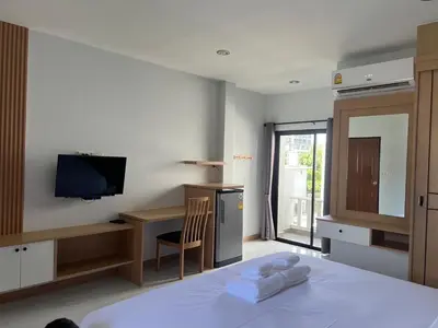 a bedroom with a bed and a desk and a television at J2 Airport Mansion in Nai Yang Beach