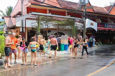 a group of people walking down a street in the rain at Andaman Seaside Resort Bangtao Beach in Bang Tao Beach
