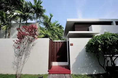 a white building with a red door and a palm tree at Malisa Villa Suites - SHA Extra Plus in Kata Beach